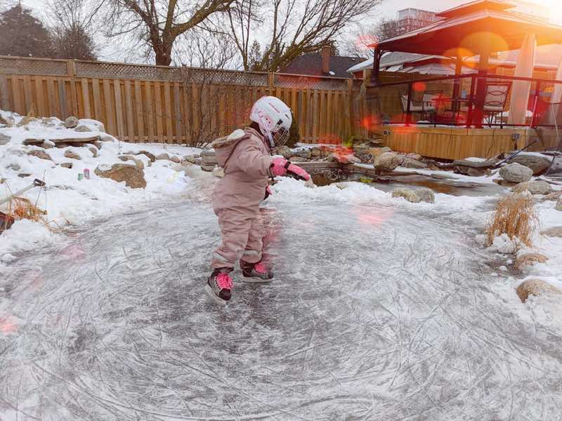 Child skating on a frozen backyard pond in winter